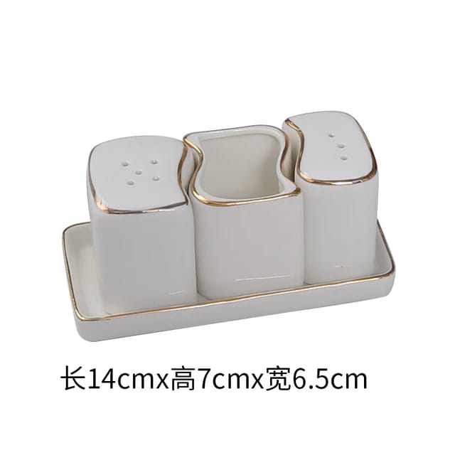 A white ceramic salt shaker with gold accents on the tray and shaker, displayed on a white background.