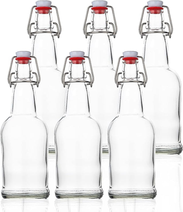 Set of six clear glass bottles with red caps on a white background