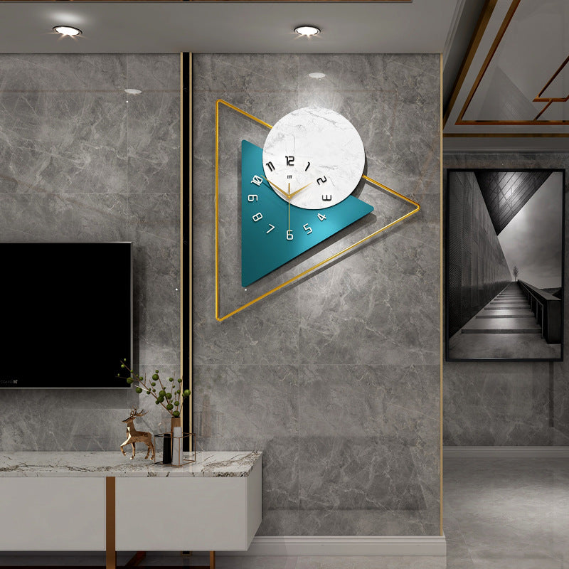 A modern style wall clock with a geometric design, featuring a blue clock face and white triangular background, mounted on a wall in a stylish interior setting.