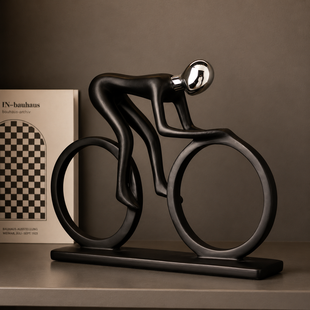 Modern abstract cyclist sculpture in matte black with a chrome head, mounted on a bicycle-shaped base, displayed as a contemporary home and office décor accent