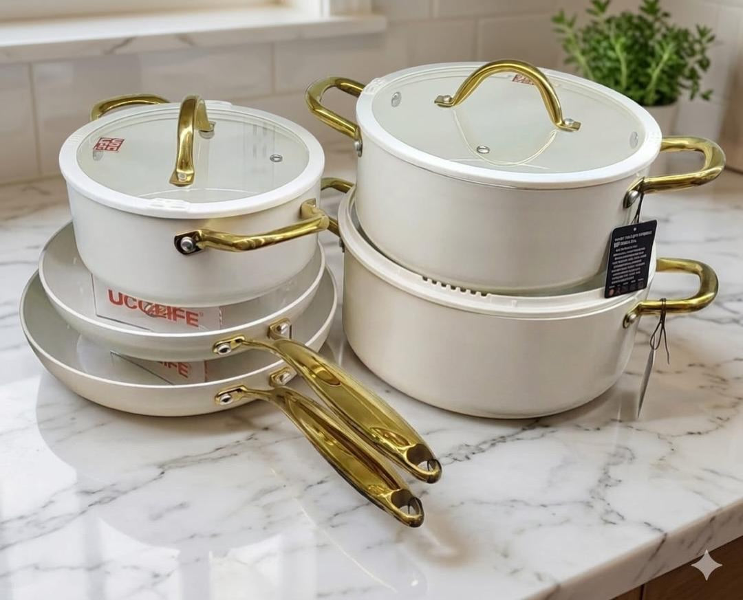 UCC Life 11-piece ceramic marble non-stick cookware set in matte black and cream white with gold handles, glass lids and silicone utensils on shelf