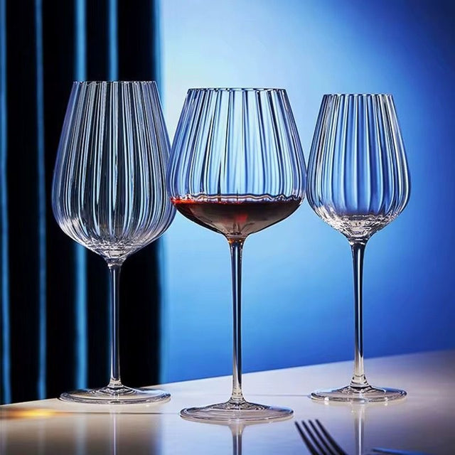 A set of three clear crystal wine glasses with a ribbed design, displayed against a blue background.