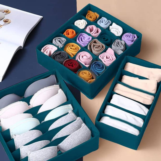 A set of drawer organizer inserts in a teal color, displayed with various folded socks and underwear neatly arranged within them.