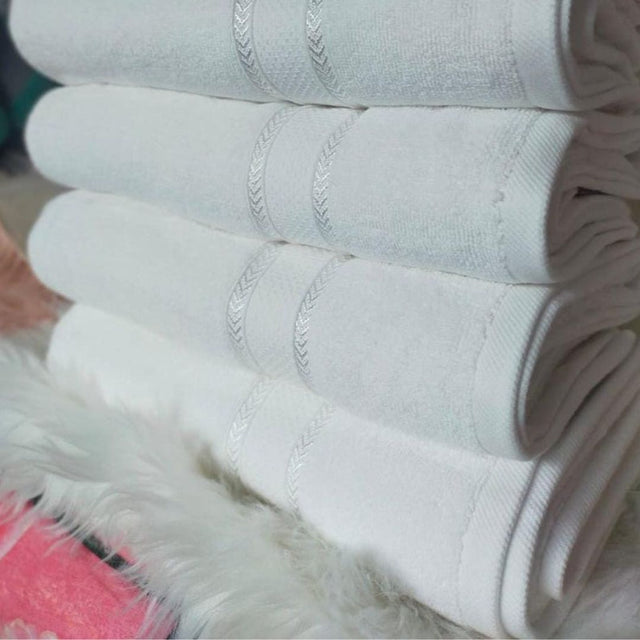 A stack of folded white towels on a flat surface, with a visible textured pattern on the towels.