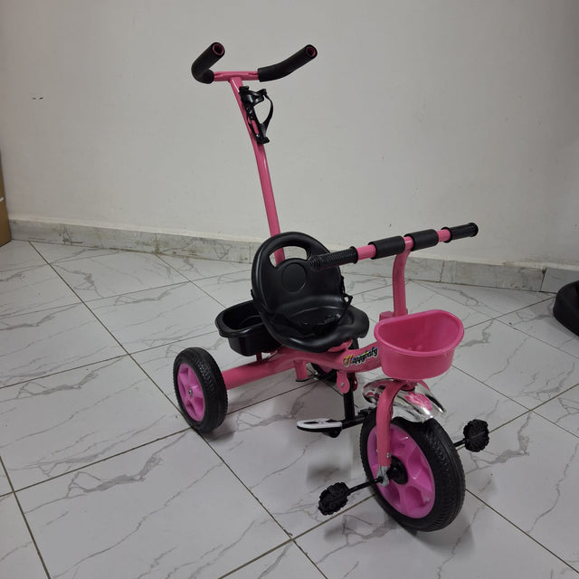 A pink tricycle with a black seat and wheels, featuring a push handle on a white tiled floor.