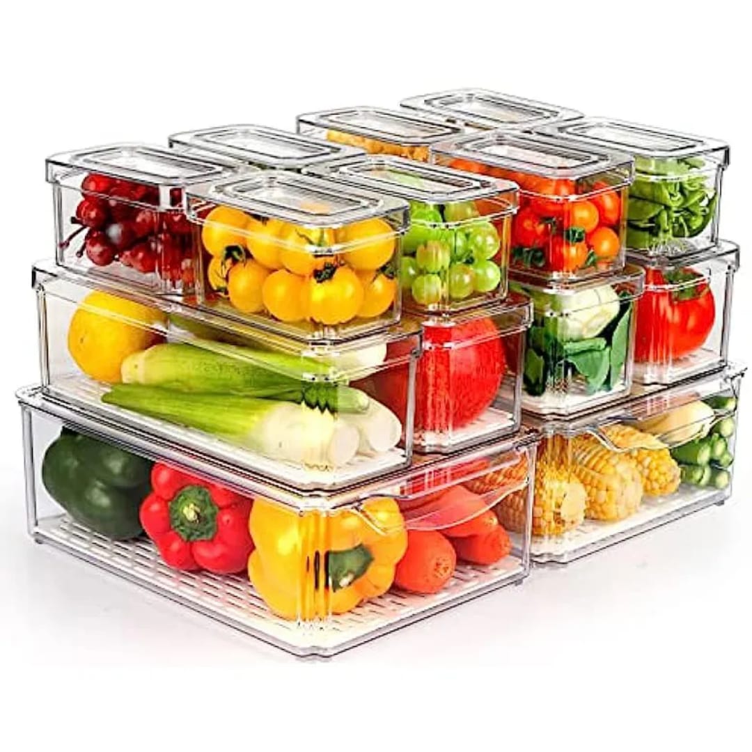 A set of stackable clear acrylic fridge organizer bins with lids, filled with various fruits and vegetables.