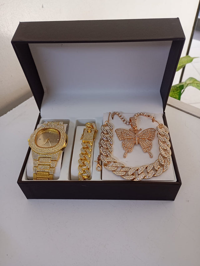 Set of gold jewelry including a watch, bracelet, and necklace with butterfly design in a black box.