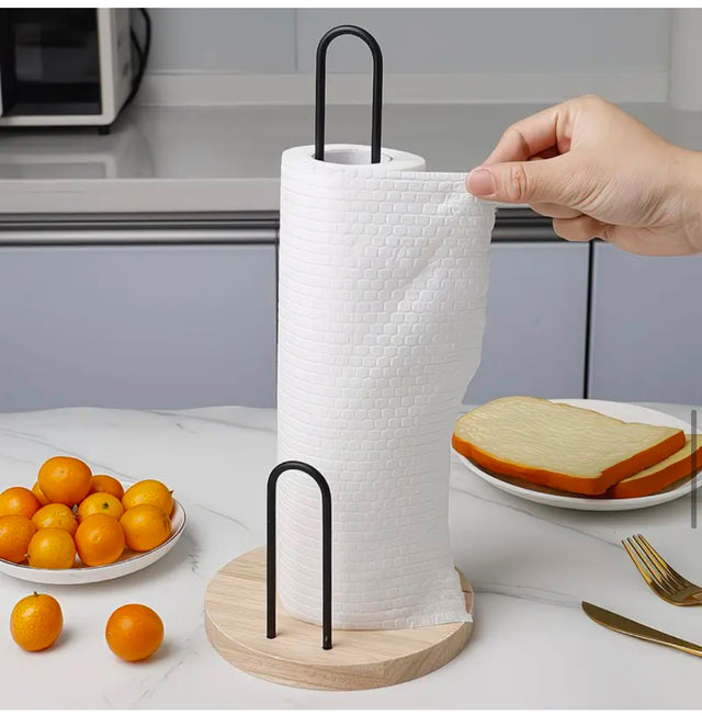 Kitchen paper towel holder with wooden base and black metal frame for countertop paper towel roll storage.