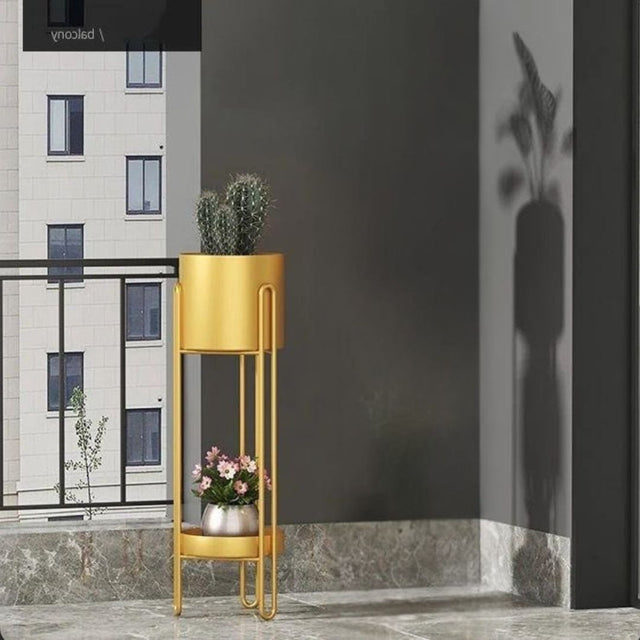 Gold plant stand with decorative plants against a dark wall.