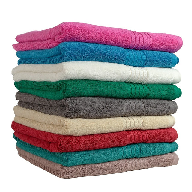 A stack of folded towels in various colors including pink, blue, white, green, beige, red, and gray.