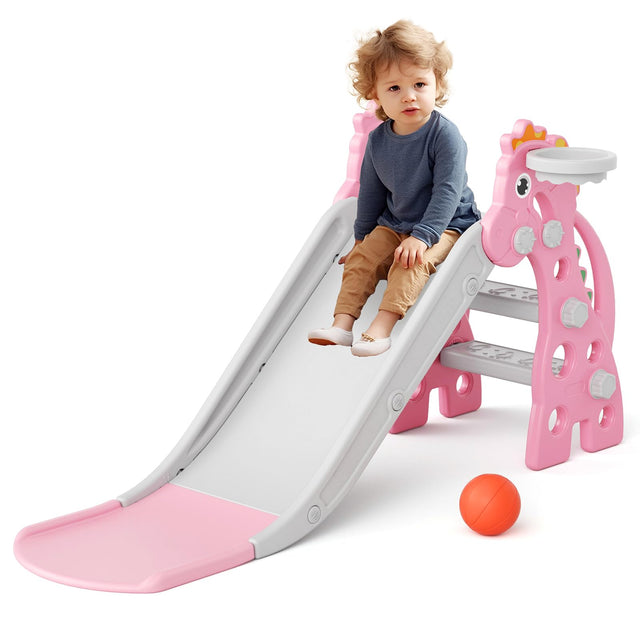 Pink and white plastic toddler slide for kids aged 1.5 to 3 years, with a smooth sliding surface, extended pink landing base, mini basketball hoop, climbing pegs, and a basketball included — indoor children's play set available at iDecorators KeNYA