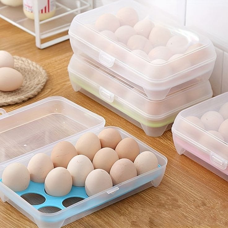 A set of transparent plastic egg storage containers with lids, one container is open displaying eggs inside, placed on a kitchen counter.