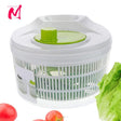 A white salad spinner with a green lid, displayed with tomatoes and lettuce leaves around it.