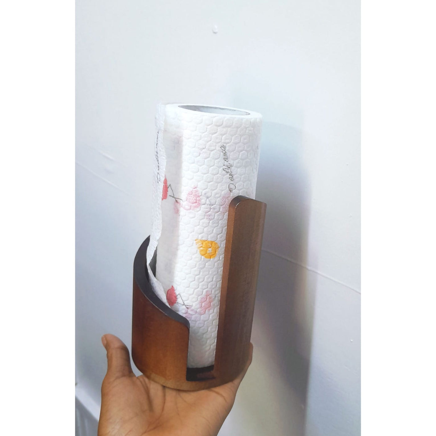 Walnut brown wooden freestanding paper towel holder measuring 15cm tall by 10cm wide, with curved cylindrical body, black metal spindle and open front slot, holding a white tissue roll on a kitchen countertop — available at iDecorators Kenya, Nairobi.