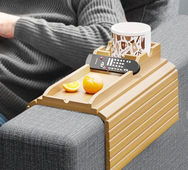 
Foldable natural bamboo sofa armrest tray measuring 16.3 by 13.3 inches with 5.1-inch built-in cup holder box, phone slot and flat surface for remote and snacks, shown clipped over a grey couch arm with a mug and TV remote — available at iDecorators Kenya, Nairobi.