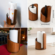 Walnut brown wooden freestanding paper towel holder measuring 15cm tall by 10cm wide, with curved cylindrical body, black metal spindle and open front slot, holding a white tissue roll on a kitchen countertop — available at iDecorators Kenya, Nairobi.