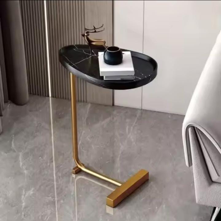 Modern side table with black marble top and gold legs in a room setting.