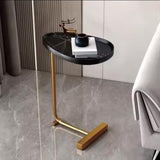 Modern side table with black marble top and gold legs in a room setting.