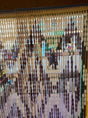 A plastic salon curtain with clear and opaque sections hanging on a rod, with people partially visible behind it.