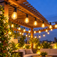 String lights black cable warm Edison style bulbs on rooftop pergola at night — iDecorators Kenya
