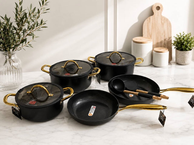 UCC LIFE 11-piece ceramic cookware set with marble non-stick coating, three casseroles with glass lids, saucepan, two deep frying pans, and gold handles in black and white.