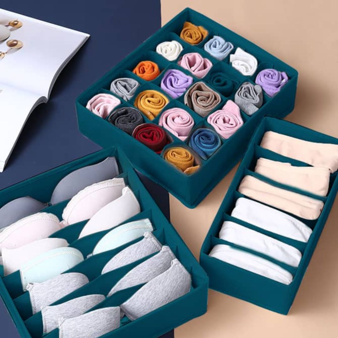 A set of drawer organizer inserts in a teal color, displayed with various folded socks and underwear neatly arranged within them.