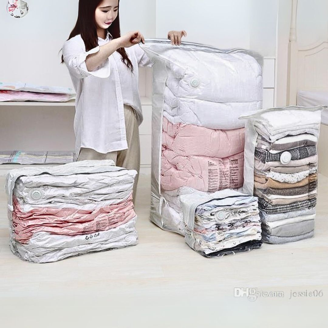 A person organizing vacuum storage bags of different sizes, with clothes and blankets inside them, displayed in a home setting.