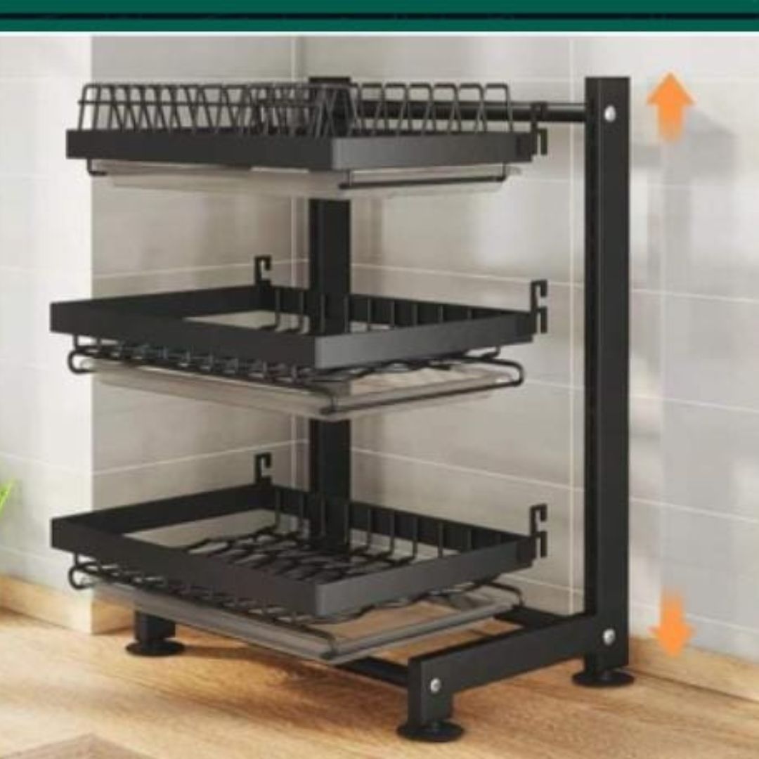 3-layer black dish rack with drain trays, chopping board, and cutlery holders, positioned in a kitchen setting with arrows indicating adjustability and flexibility in placement.