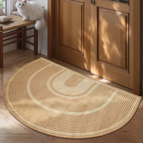 Semi-circle jute rug on a wooden floor with a wooden door in the background.