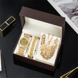 Gold jewelry set including a watch, bracelet, and necklace in an open box on a dark surface.