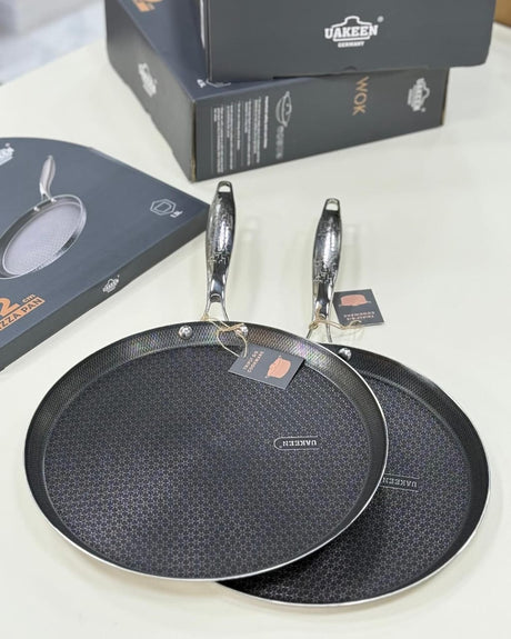 Two black frying pans with a textured surface on a white background, accompanied by their packaging.