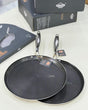 Two black frying pans with a textured surface on a white background, accompanied by their packaging.