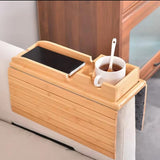 Foldable natural bamboo sofa armrest tray measuring 16.3 by 13.3 inches with 5.1-inch built-in cup holder box, phone slot and flat surface for remote and snacks, shown clipped over a grey couch arm with a mug and TV remote — available at iDecorators Kenya, Nairobi.