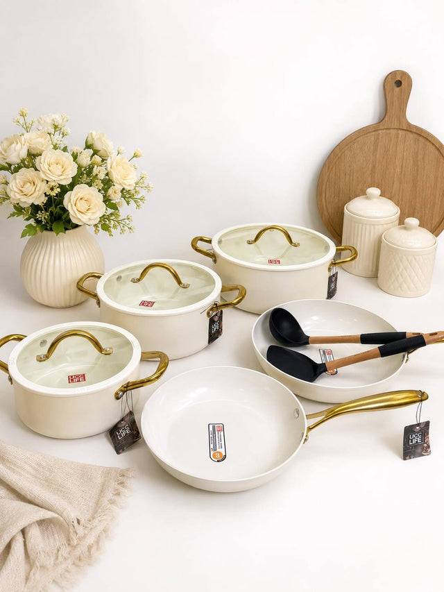 WHITE UCC LIFE 11-piece ceramic cookware set with marble non-stick coating, three casseroles with glass lids, saucepan, two deep frying pans, and gold handles in black and white.