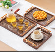 Luxury rectangular serving trays with a marble-pattern surface, wooden frame, and gold-tone handles, styled with a teapot, teacup, pastries, and assorted dried fruits on a wooden table.