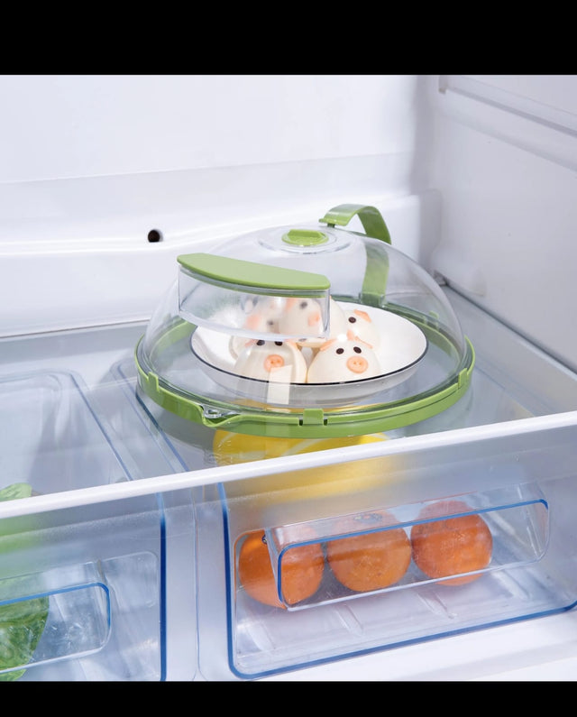 Transparent microwave food cover with green handle and steam vent protecting food from splatters during reheating.