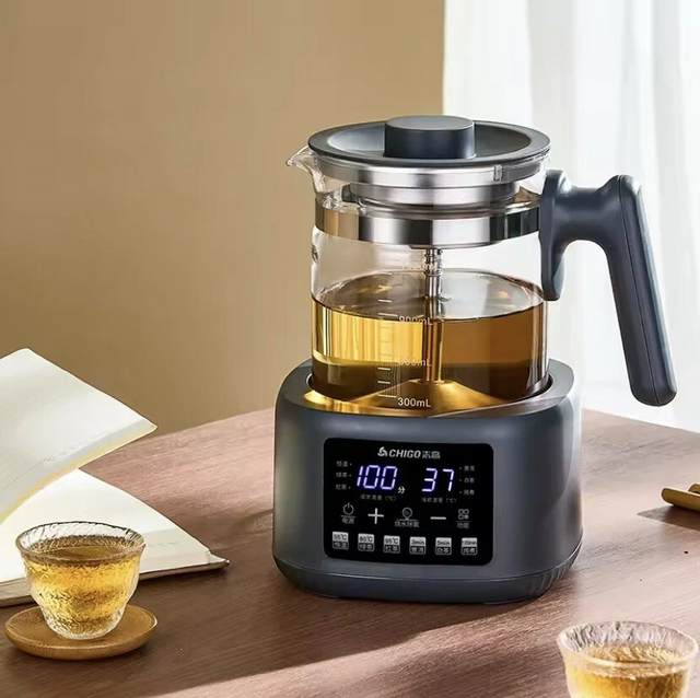 Chigo smart electric health pot and tea maker with LED digital display, glass carafe and stainless steel infuser on wooden table with tea cups