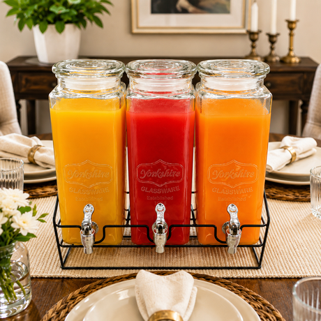 Three glass beverage dispensers with chrome taps mounted on a black metal stand for serving juice and cold drinks.