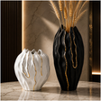 Modern black and white ceramic vase set with gold accents displayed on a marble tabletop.