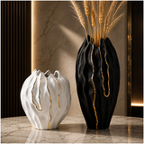Modern black and white ceramic vase set with gold accents displayed on a marble tabletop.