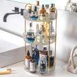 3-tier 360-degree rotating makeup and skincare organiser with gold metal arch frame, clear ribbed acrylic round trays measuring 16.9 inches tall, 9 inches wide base, 2 inch deep trays with 4.4 and 6.6 inch tier spacing, filled with perfume and skincare products on a vanity counter — available at iDecorators Kenya, Nairobi.