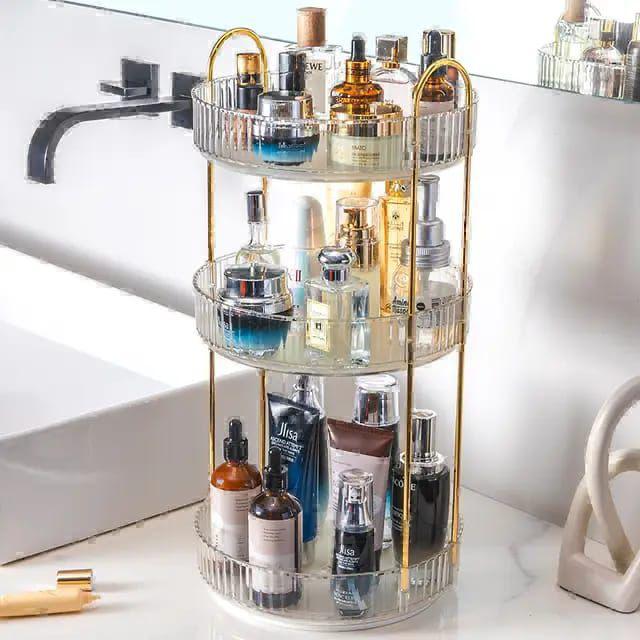 3-tier 360-degree rotating makeup and skincare organiser with gold metal arch frame, clear ribbed acrylic round trays measuring 16.9 inches tall, 9 inches wide base, 2 inch deep trays with 4.4 and 6.6 inch tier spacing, filled with perfume and skincare products on a vanity counter — available at iDecorators Kenya, Nairobi.