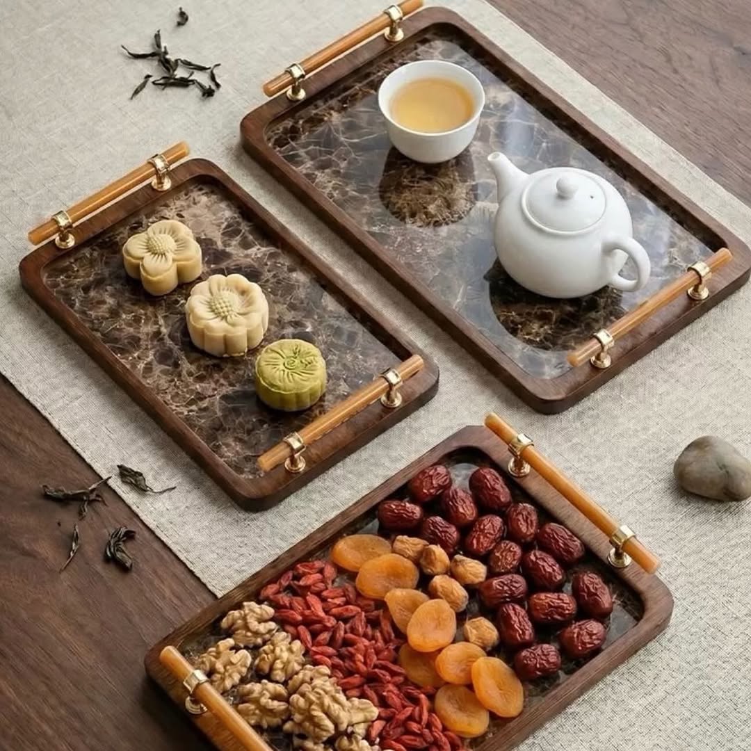 Luxury rectangular serving trays with a marble-pattern surface, wooden frame, and gold-tone handles, styled with a teapot, teacup, pastries, and assorted dried fruits on a wooden table.