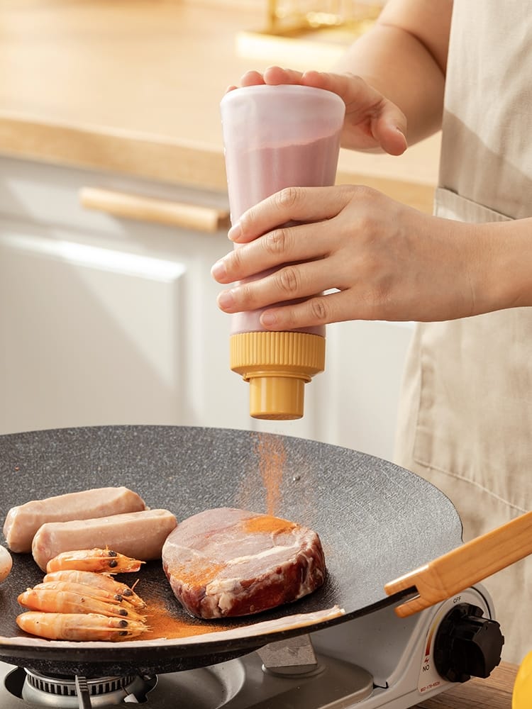 350ml Heburn powder seasoning shaker bottles with flip caps in cream white, navy blue and mustard yellow, shown on a wooden kitchen counter beside a grilling pan — spice dispenser bottles available at iDecorators Kenya, Nairobi.