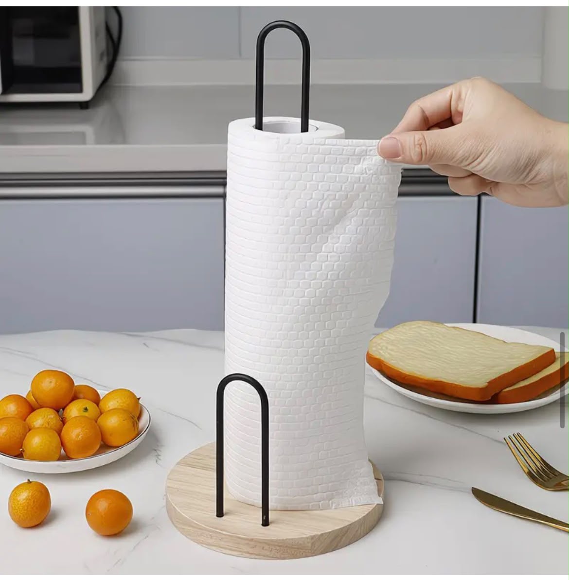 Kitchen paper towel holder with wooden base and black metal frame for countertop paper towel roll storage.