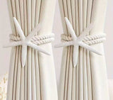 White starfish curtain tiebacks with twisted rope securing cream-colored curtains.