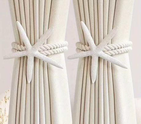 White starfish curtain tiebacks with twisted rope securing cream-colored curtains.