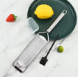 Premium stainless steel fine grater with protective cover and cleaning brush for grating cheese, lemon zest, garlic, ginger, chocolate, and spices.