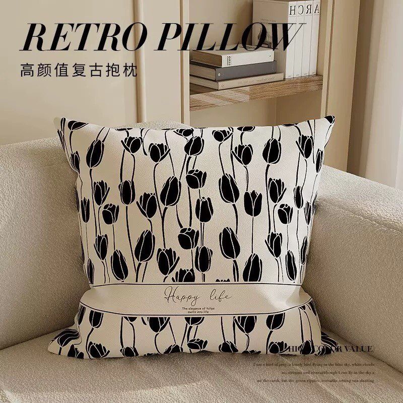 Decorative pillow with black tulip pattern on a beige sofa