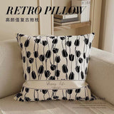 Decorative pillow with black tulip pattern on a beige sofa